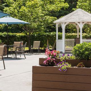 A peaceful outdoor patio featuring a gazebo, tables with chairs, and potted plants.