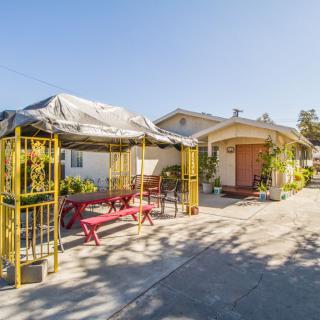 A sunny outdoor area with a covered patio and seating arrangements next to a building.
