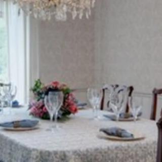 An elegantly set dining table with a floral centerpiece and a chandelier overhead.