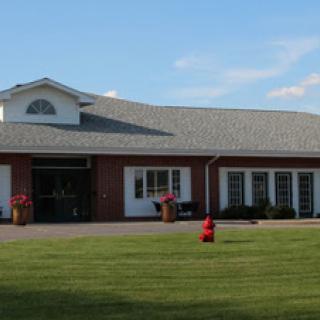 A well-maintained brick building with a spacious lawn and clear blue skies.