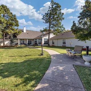 A scenic backyard view of a residential house with a spacious lawn and patio area.