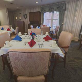 A dining room with tables elegantly set with red and blue napkins, ready for service.