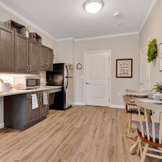 A modern kitchen interior with wooden flooring, dark cabinets, and a small dining area.