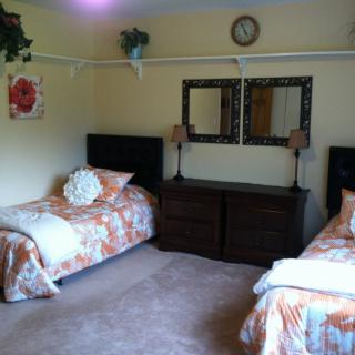 A cozy bedroom with two twin beds, decorative mirrors, and warm tones.