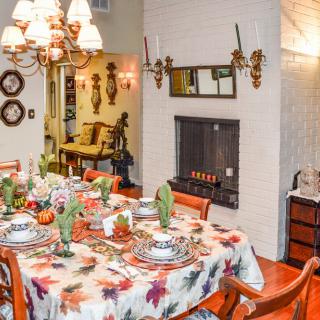 A warmly decorated dining room with a festive table setting and cozy fireplace.