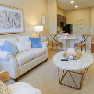 A cozy living room with modern decor, featuring a white sofa, a round marble coffee table, and an open floor plan leading to the kitchen area.