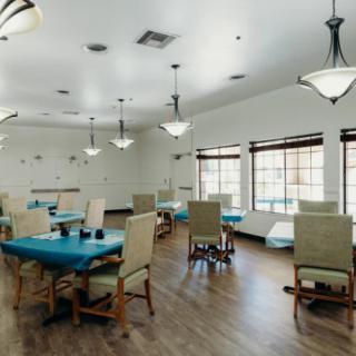 A spacious dining room with tables and chairs, featuring large windows and elegant lighting.