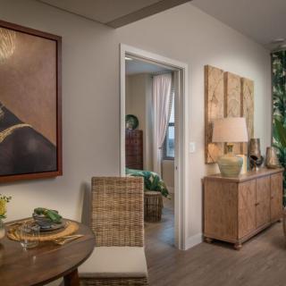 A cozy living room with warm lighting, featuring a dining area, artwork on the walls, and natural wooden furniture.