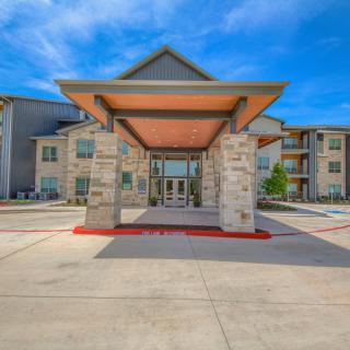 A modern three-story building with a stone exterior and a covered entrance.