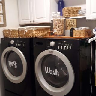 A neatly organized laundry room with a washer and dryer, featuring storage baskets and jars.