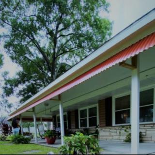 A charming house with a spacious porch and lush greenery surrounding it.