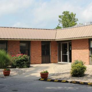 A brick building with plants in front and a visible entrance.