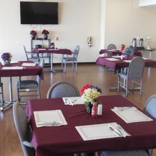 A welcoming dining area set up with tables adorned in purple tablecloths, creating a cozy atmosphere for guests.