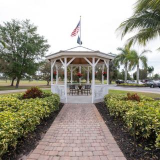 A gazebo with flags on top, surrounded by a brick pathway and landscaped greenery.