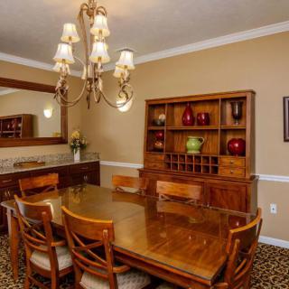 A well-furnished dining room with a large wooden table, matching chairs, and a decorative chandelier.
