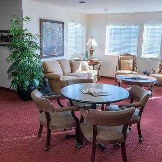 A cozy living room with comfortable seating, a round table, and natural light from the windows.