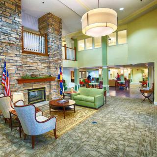 A modern lobby with comfortable seating, a fireplace, and flags on display.