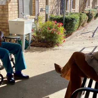 Two individuals sitting outdoors, enjoying a conversation in the sunlight.