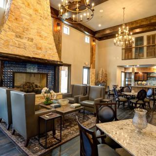 A spacious living room featuring a large stone fireplace, elegant chandeliers, and comfortable seating.
