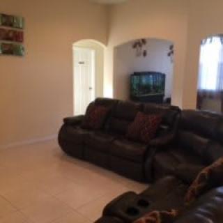 A cozy living room with dark leather sofas and a television.
