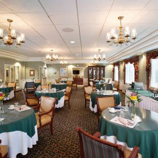 A formal dining room with elegantly set tables and chandeliers.