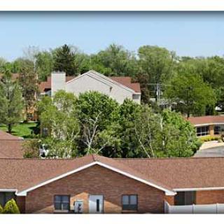 A suburban landscape featuring buildings and lush green trees under a clear sky.