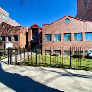 A view of a brick building with a fenced yard under a clear blue sky.