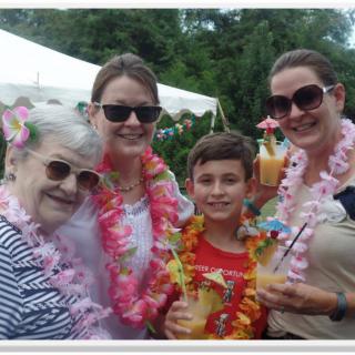 A family enjoying a tropical-themed celebration outdoors with leis and drinks.