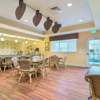 A cozy dining area with wooden floors, tables, and chairs, adorned with ceiling fans and ample lighting.