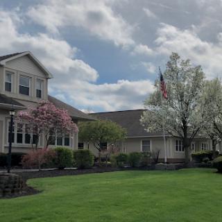 A beautiful residential area featuring a well-maintained house and garden under a partly cloudy sky.