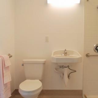 A minimalist bathroom with a toilet, sink, and towel rack.