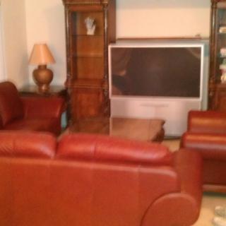 A cozy living room with leather sofas and a large television.