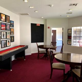 A cozy game room with a shuffleboard table, seating, and wall art.