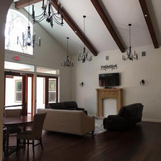 A spacious living room featuring high ceilings, elegant chandeliers, and a cozy fireplace.