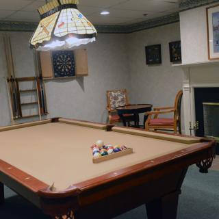 A cozy game room featuring a billiards table and a dartboard on the wall.