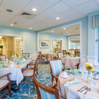 An elegantly decorated dining room with neatly arranged tables and chairs, set for a meal.