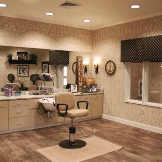 A cozy salon interior with a central chair, mirror, and warm lighting.