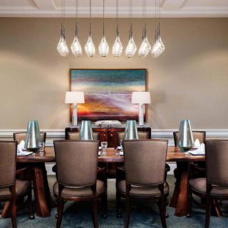 Elegant dining room with a large table, stylish chairs, a modern chandelier, and vibrant artwork.
