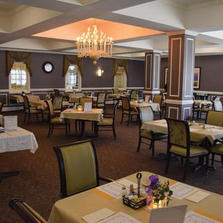A well-decorated dining room with neatly arranged tables and a chandelier.