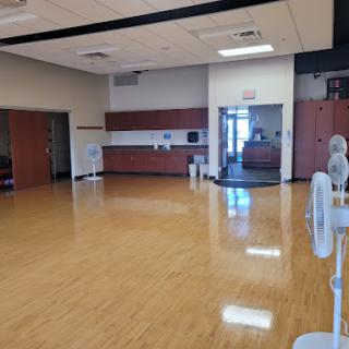 A spacious and well-lit gym area with polished wooden flooring, ready for various fitness activities.