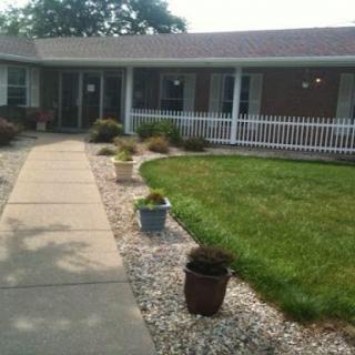 A welcoming front yard featuring a well-maintained lawn, decorative potted plants, and a paved walkway leading to the house.
