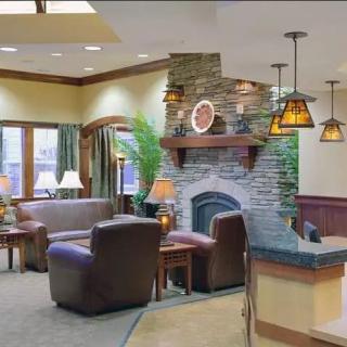 A cozy living room featuring a stone fireplace surrounded by leather seating and warm lighting.