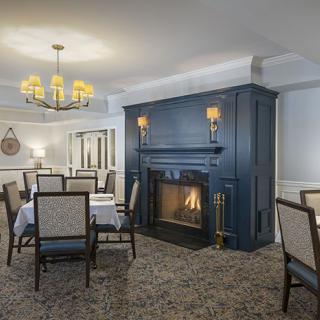 A cozy dining room featuring a blue fireplace and elegant chandelier.