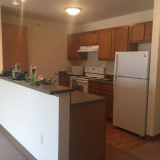 A cozy apartment kitchen with wooden cabinets and modern appliances.