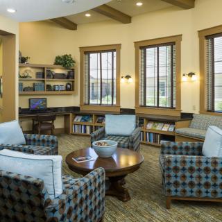 A cozy living room with comfortable seating, bookshelves, and large windows.