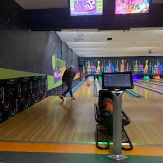 A person enjoying a game of bowling in a vibrant, illuminated bowling alley.