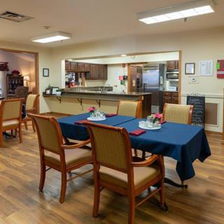 A cozy dining area with tables and chairs, adjacent to a kitchen space.