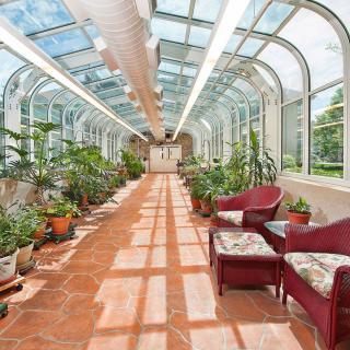 A sunlit conservatory with potted plants and comfortable seating.