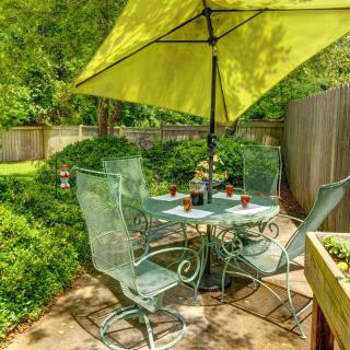 A cozy garden patio with a table and chairs set under a large green umbrella.
