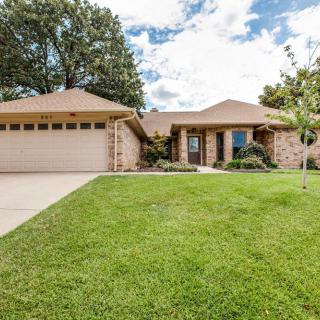 A suburban house with a spacious lawn and attached garage under a cloudy sky.